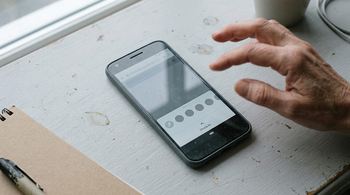 Smartphone share sheet open on a desk showing photo sharing options